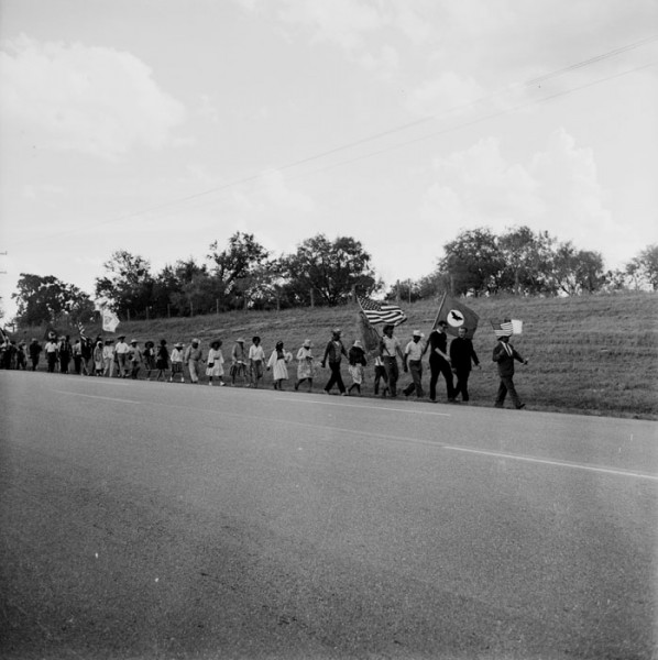 The Rio Grande Valley Farm Workers March (“La Marcha”) was among the major events in the Latino movement for economic justice in Texas during the 1960s. The impetus for the march developed after efforts to gain decent wages for farm laborers in Starr County had failed in 1966. Rev. James Novarro, pastor of Kashmere Baptist Temple in Houston and co-chairman of the march, leads the marchers – who are on their way to the capitol in Austin -- along U. S. Highway 181 near Floresville, August 24, 1966. Image # E-0012-187-B-02, San Antonio Express-News Photograph collection, MS 360, University of Texas San Antonio Libraries Special Collections.